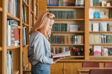 teenager-reading-near-bookshelves